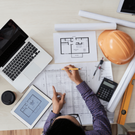 Profissional de engenharia civil desenvolvendo projetos personalizados com planta baixa e ferramentas de construção em Ipatinga